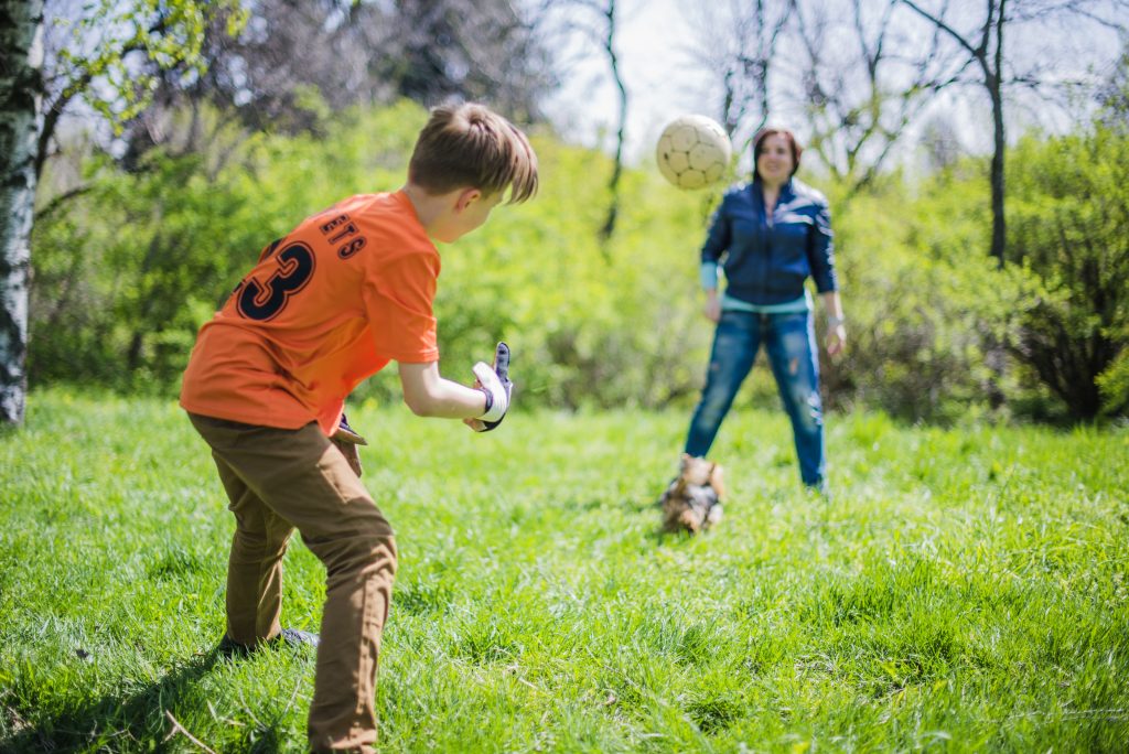 A boy and his mother play soccer in a field.