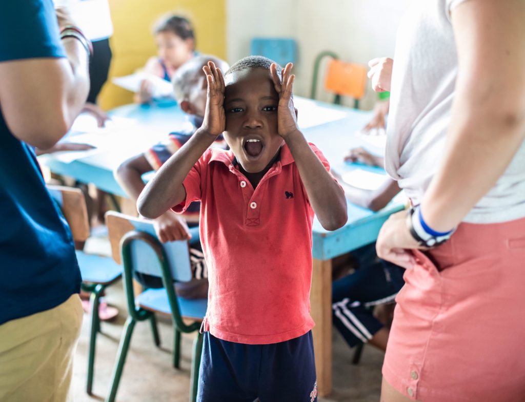 Young boy, possibly neurodivergent learner, in a classroom looking very frustrated.