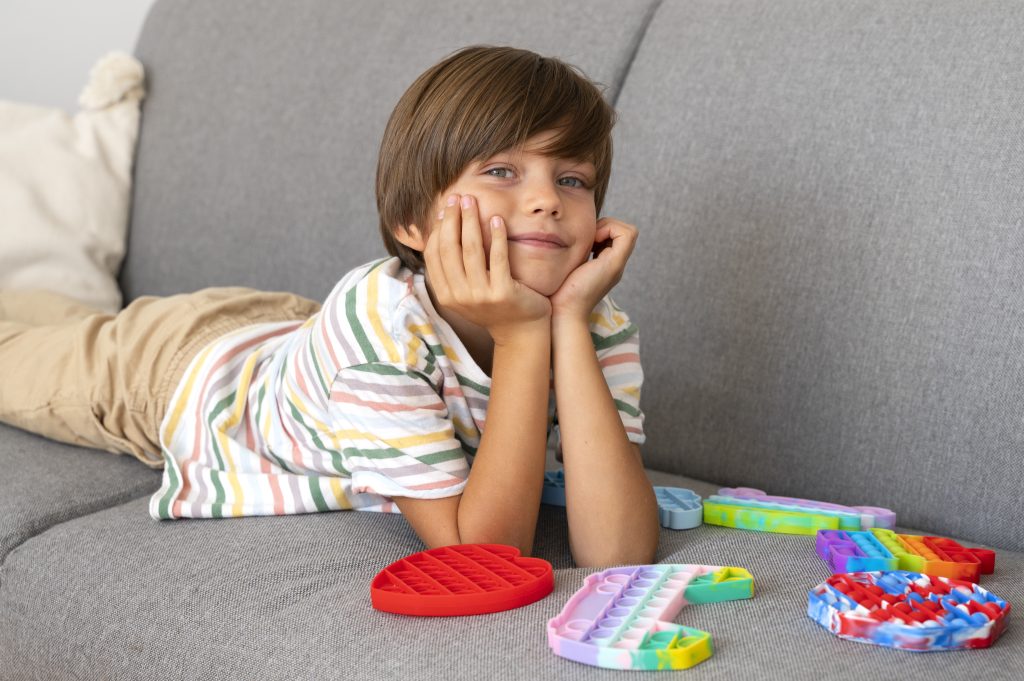 A boy lays on a couch surrounded by fidget toys for ADHD.