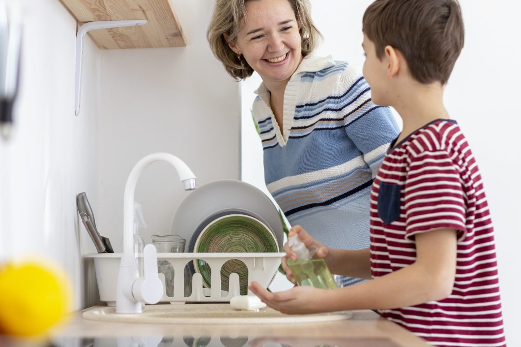 Boy does dishes with mother