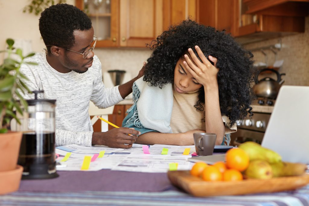 Teenager looking frustrated over school work while her dad tries to help her.