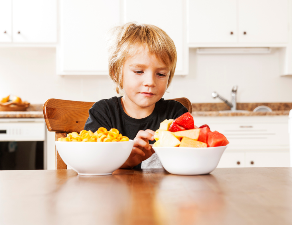 Young boy makes choice of breakfast between cereal and fruit