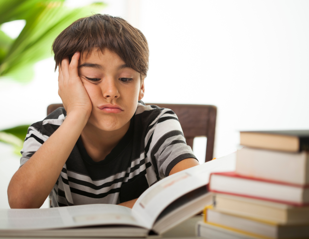 Boy looks bored over a textbook