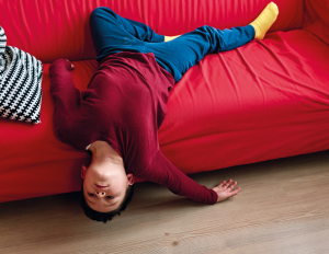 bored kid lays on red couch